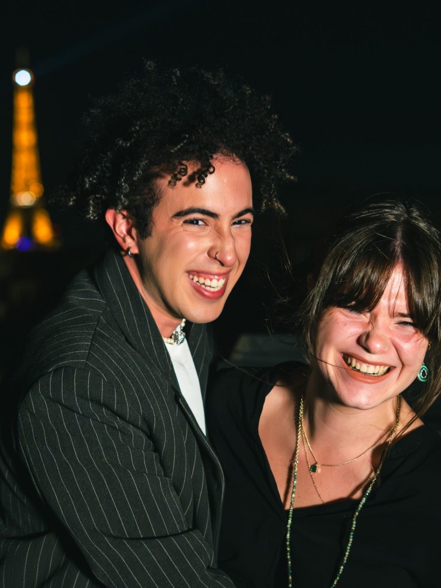 Deux personnes souriantes, avec la tour Eiffel en arrière-plan.