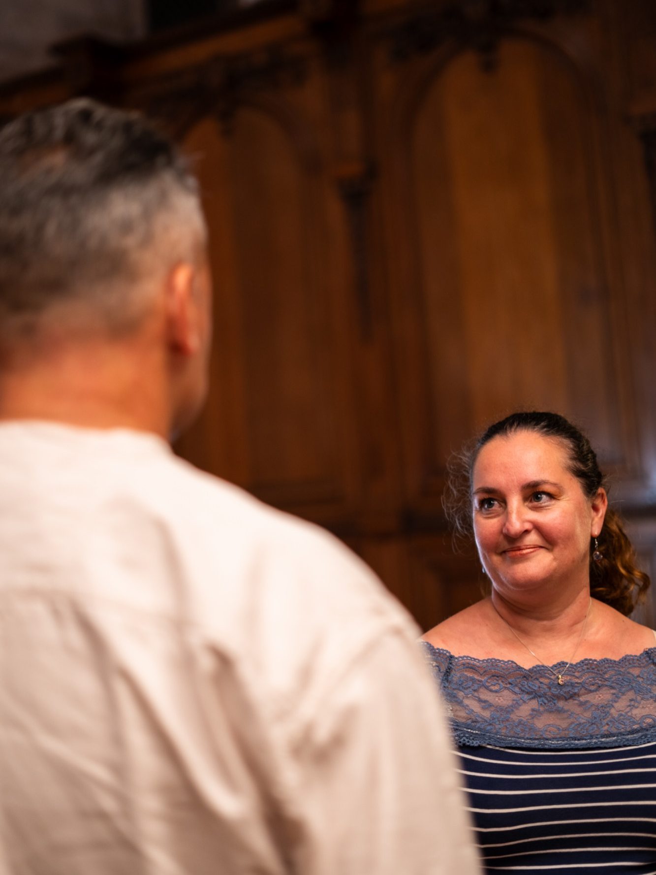 Un homme de dos sourit à une femme, dans un cadre intérieur chaleureux et convivial.