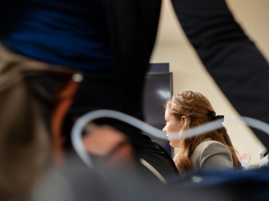 Une femme assise, concentrée, avec des câbles visibles en arrière-plan.