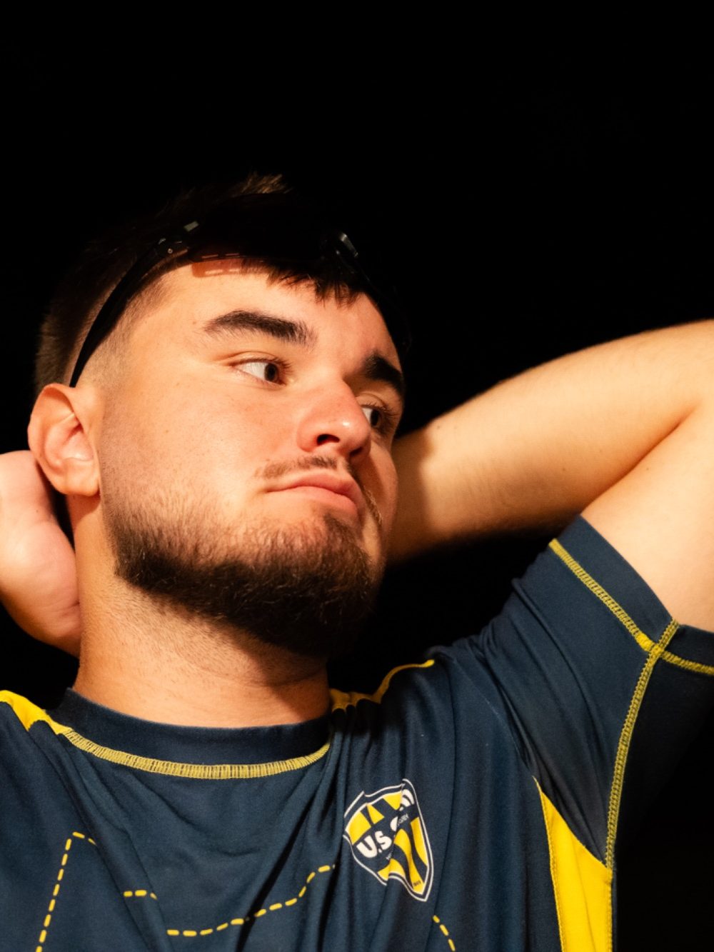 Jeune homme en t-shirt bleu, regard pensif, les bras derrière la tête.