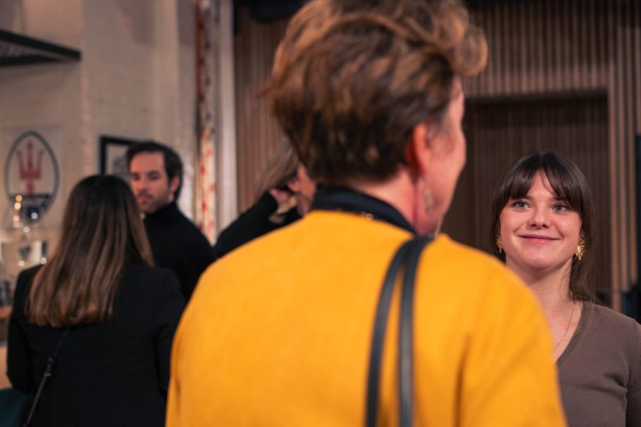 Une silhouette féminine de dos, cheveux au vent, avec un ciel lumineux en arrière-plan.