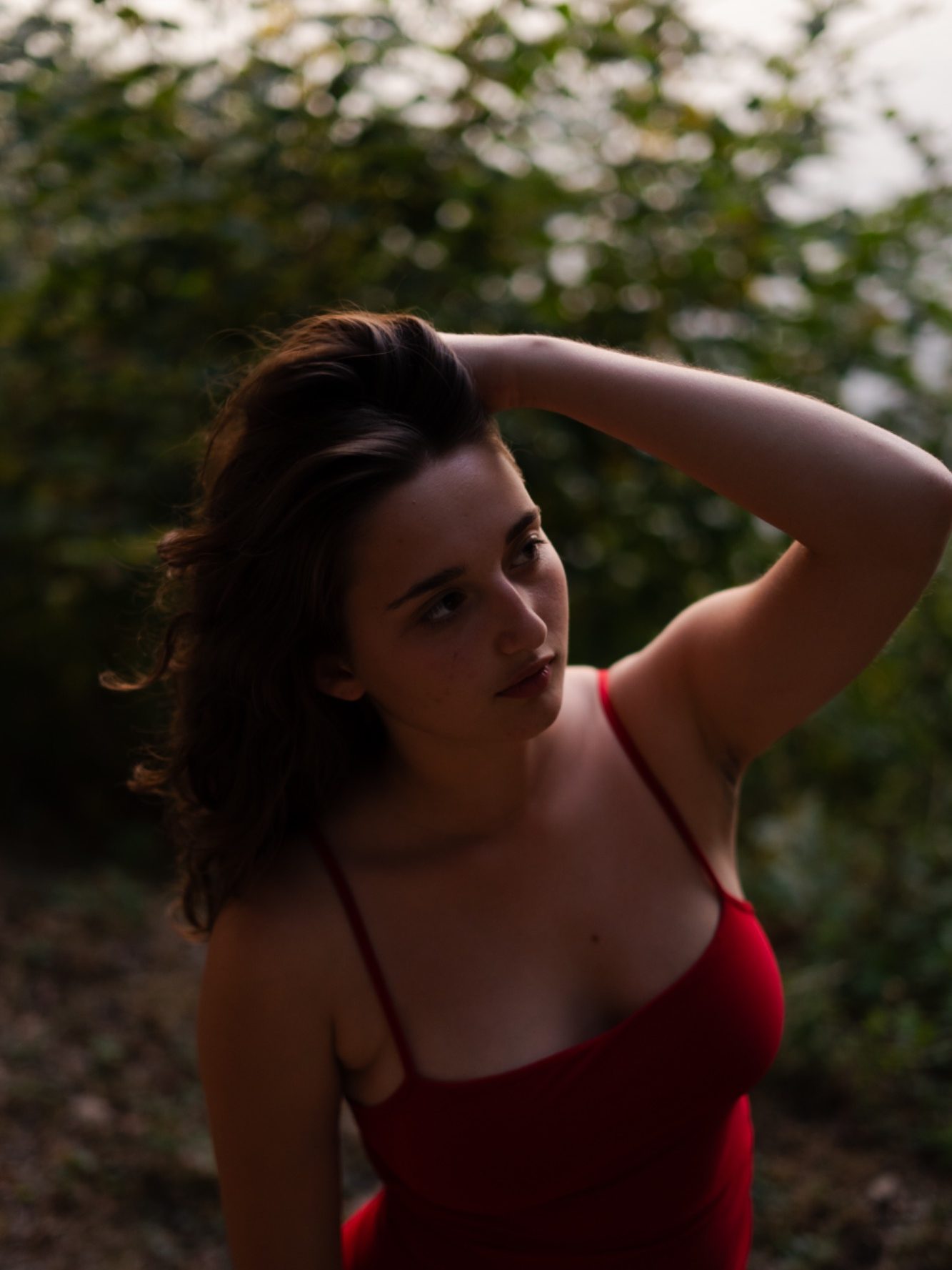Femme au regard pensif, portant une robe rouge, en pleine nature.