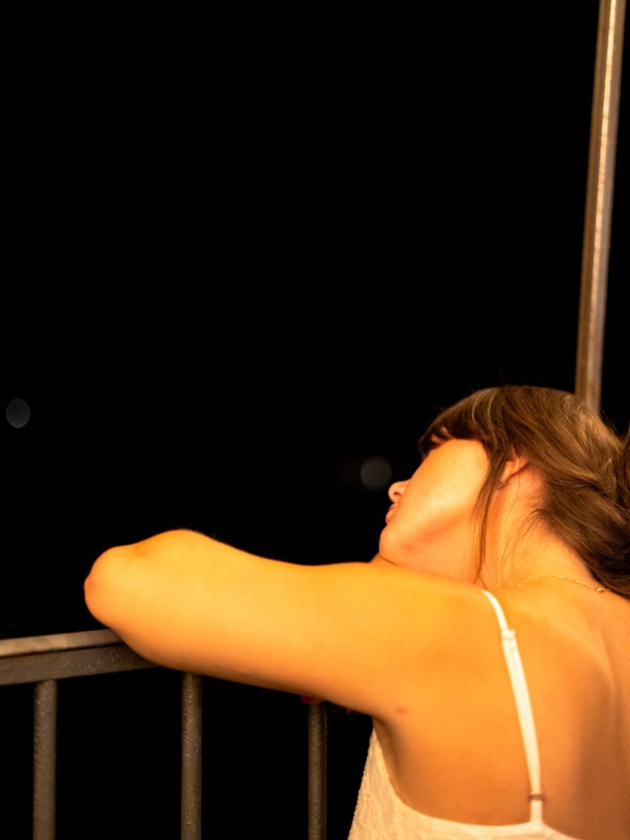 Jeune femme se penchant sur un balcon, contemplant la nuit.
