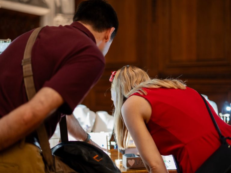 Deux personnes se penchent pour observer attentivement un objet sur une table.