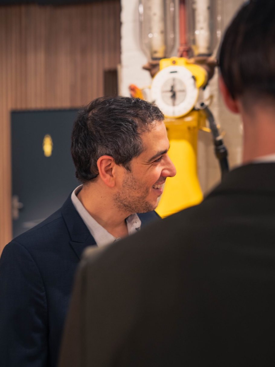 Femme souriante en arrière-plan naturel, cheveux longs, portant un haut léger.