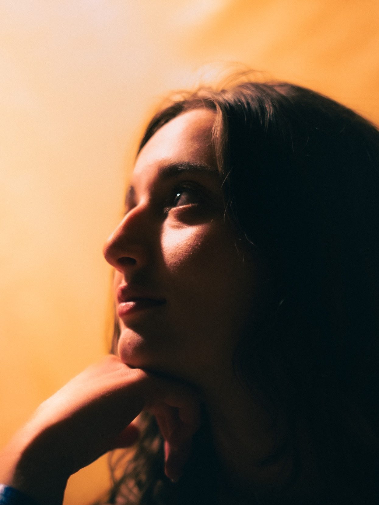 Portrait d'une jeune femme pensive, éclairée par une lumière douce.