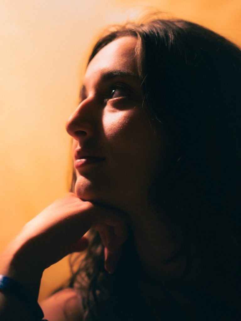 Portrait d'une jeune femme pensive, visage tourné vers la droite avec un fond lumineux.