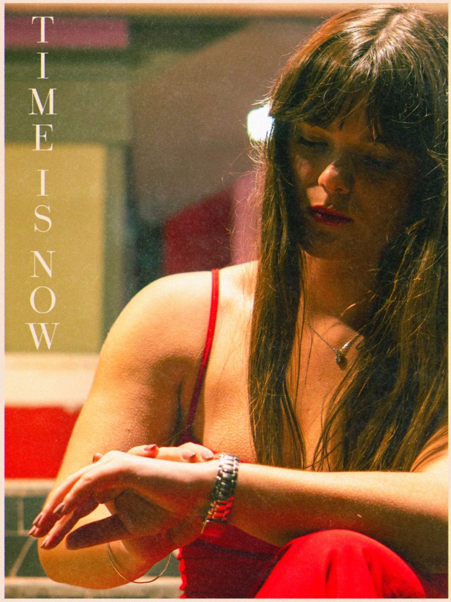 Femme avec de longs cheveux bruns, regardant une montre, vêtue d'une robe rouge.