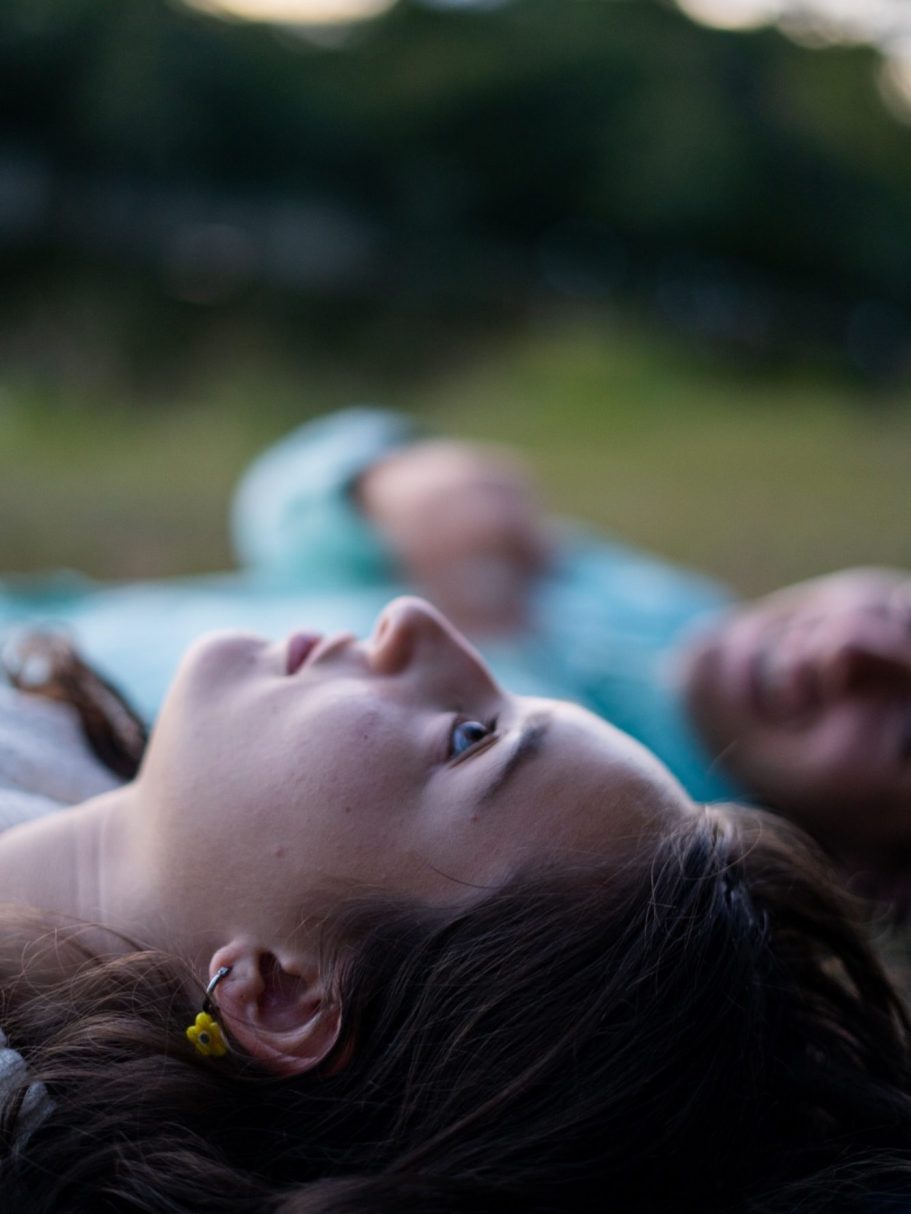 Deux personnes allongées sur le dos, regardant le ciel, l'une se concentre et l'autre se détend.