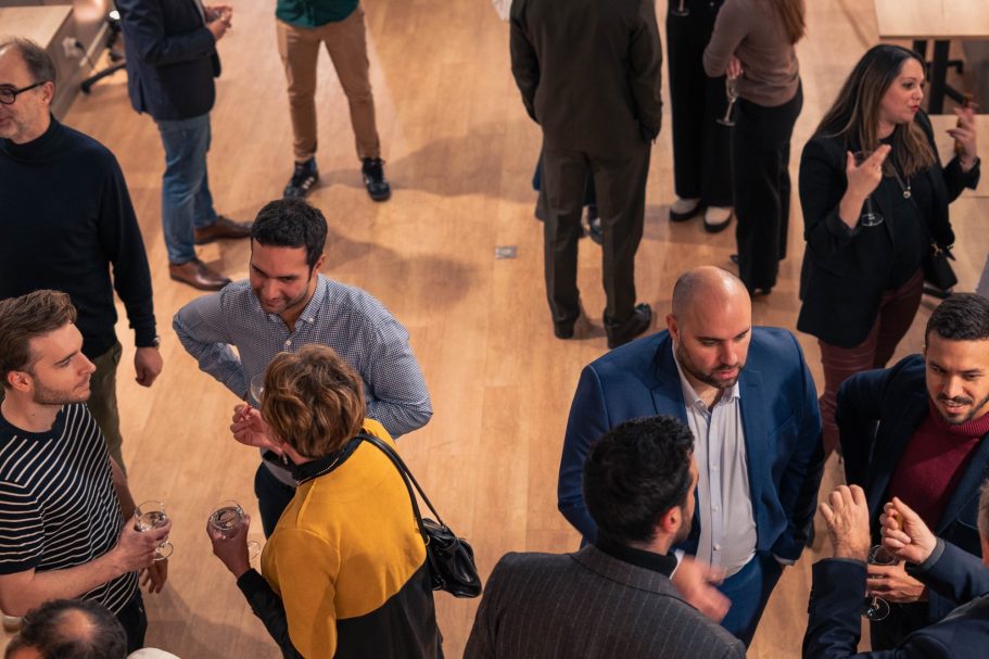 Jeune femme en robe rouge, regard pensif, cheveux au vent, arrière-plan flou.