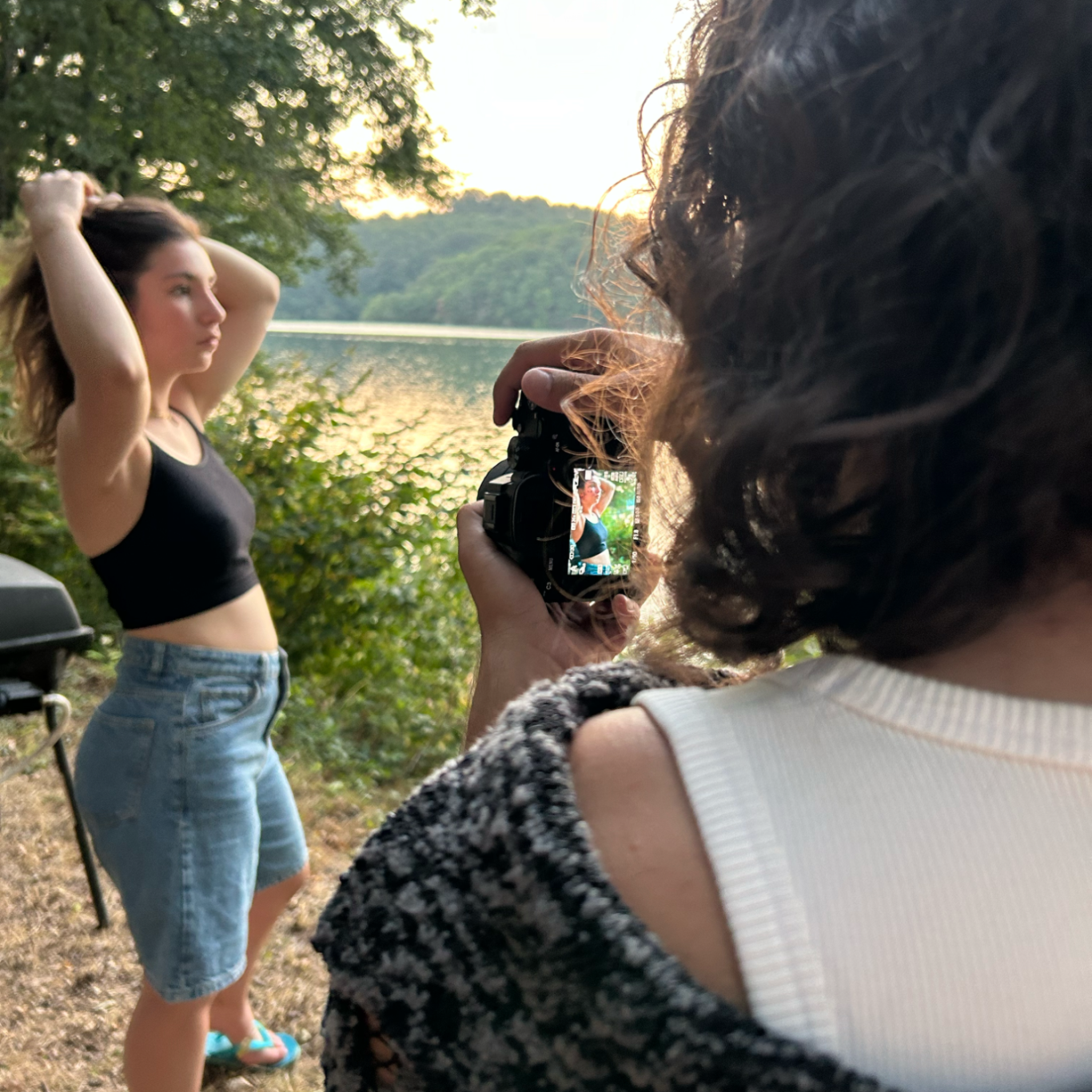 Femme posant près d'un lac, une autre personne prend une photo d'elle.