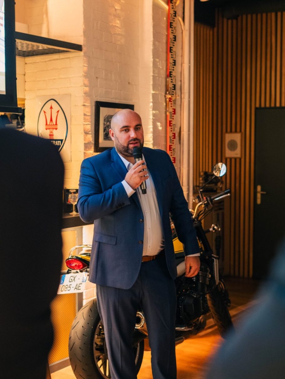 Une jeune femme assise sur une terrasse, portant une chemise colorée et un pantalon large.