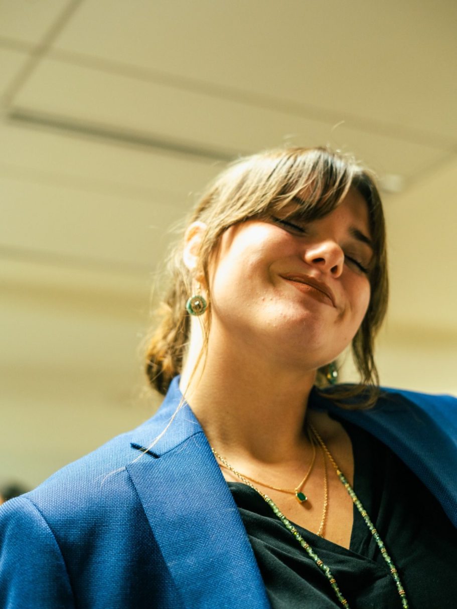 Femme souriante en blazer bleu, affichant une expression joyeuse.