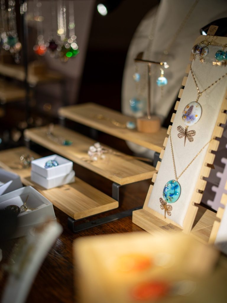 Bijoux exposés sur des supports en bois, incluant colliers et boucles d'oreilles.