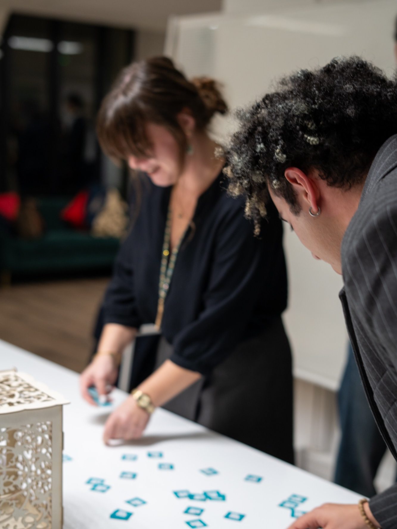 Deux personnes interagissent autour d'une table en disposant des objets couleur turquoise.