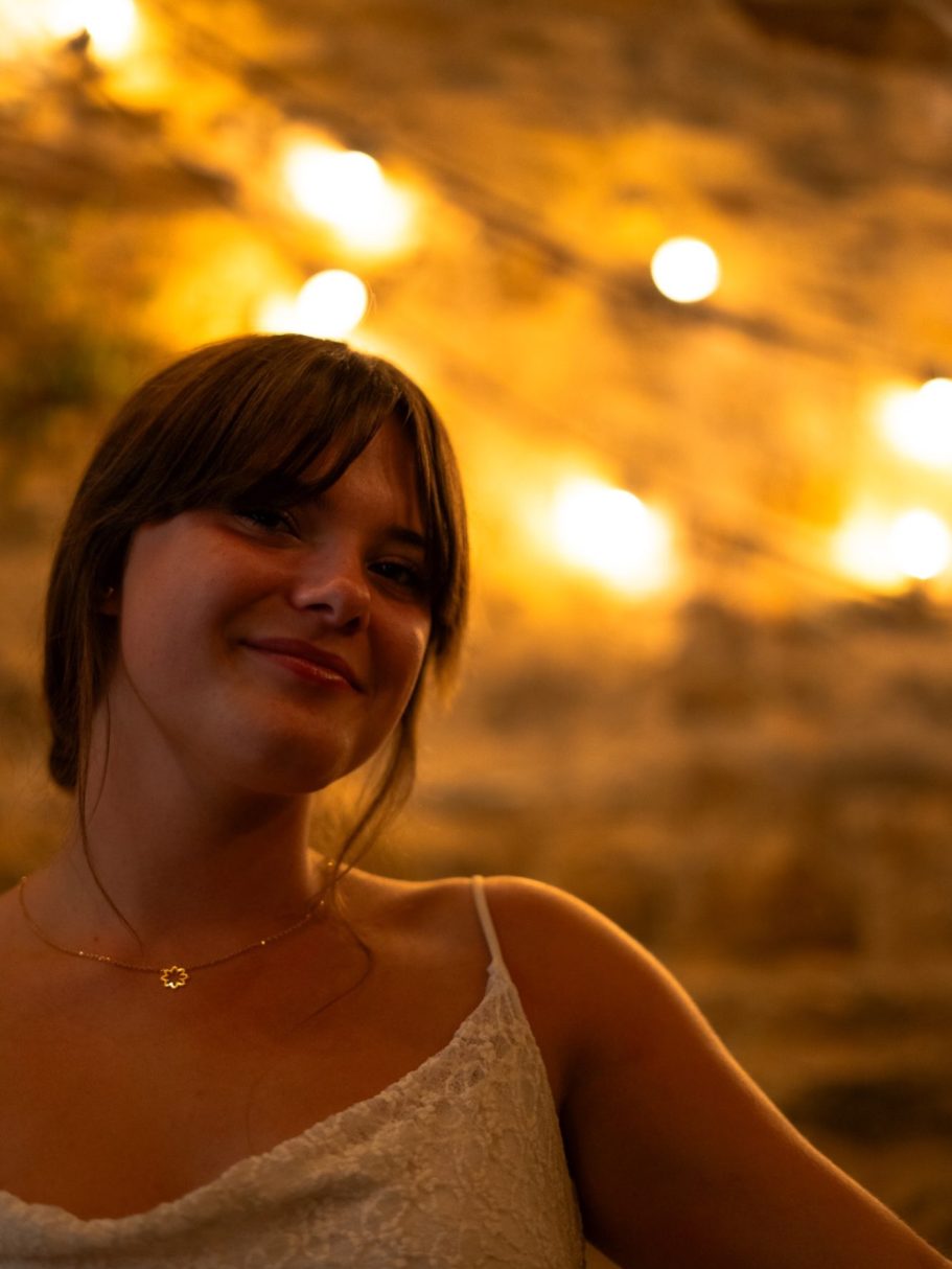 Femme souriante avec des lumières floues en arrière-plan.