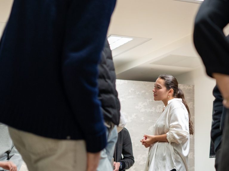 Une femme en discussions, entourée de personnes, dans un cadre moderne.