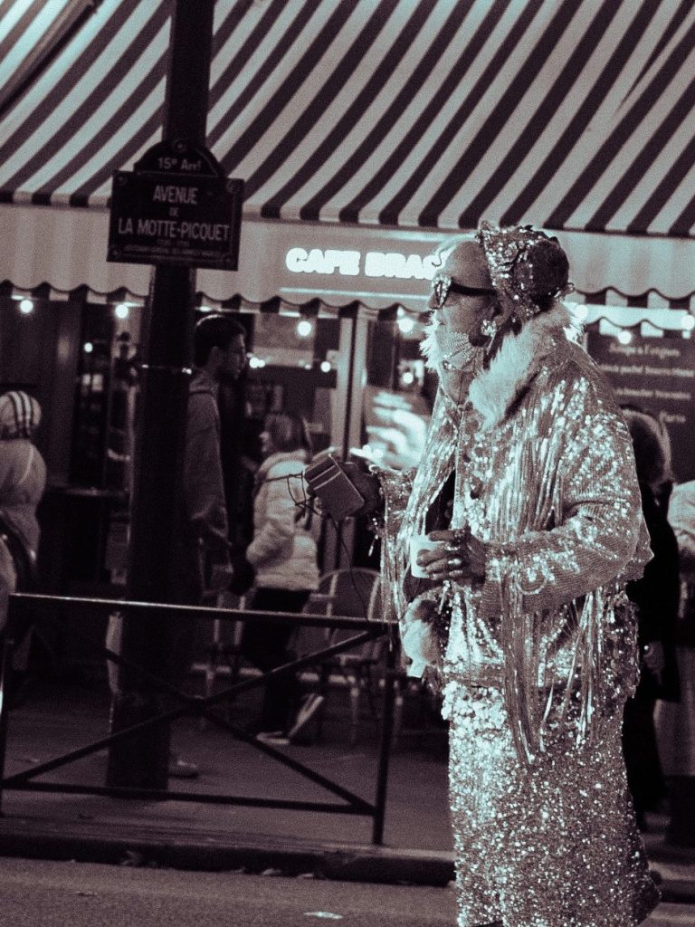 Une personne vêtue d'un costume argenté se tient sous un auvent à rayures.