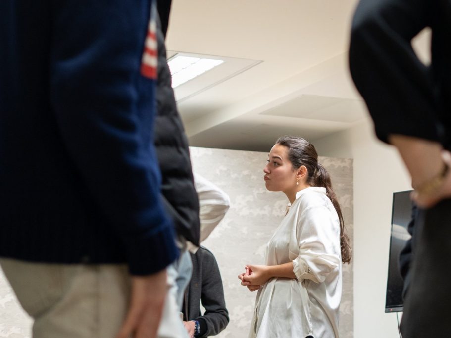 Groupe de personnes discutant, avec une femme en blanc au centre de l'attention.