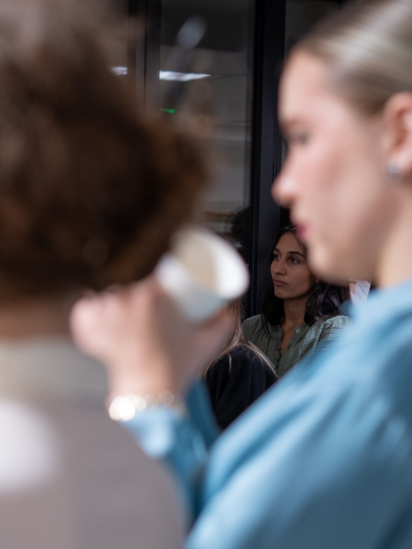 Deux femmes discutent, l'une tenant une tasse, l'autre regardant au loin.