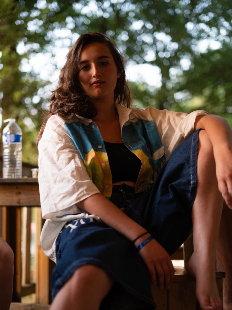 Person assise, vêtue d'une chemise colorée, avec une bouteille d'eau à côté d'elle.