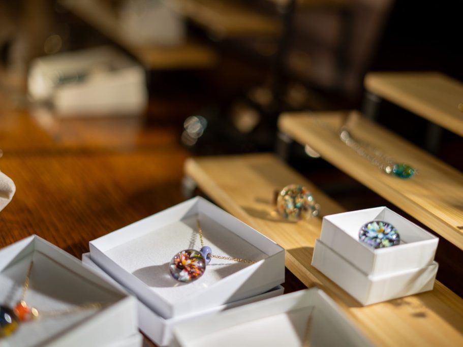 Bijoux colorés présentés dans des emballages blancs sur une surface en bois.