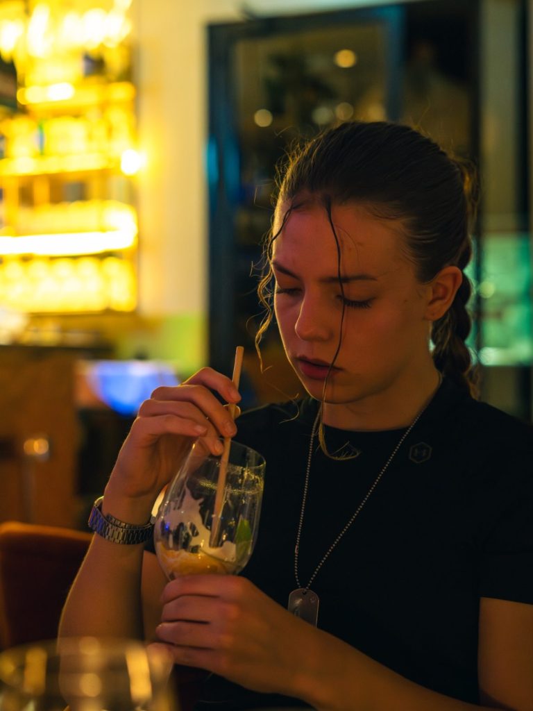 Jeune femme sirotant une boisson dans un café ambiance tamisée.