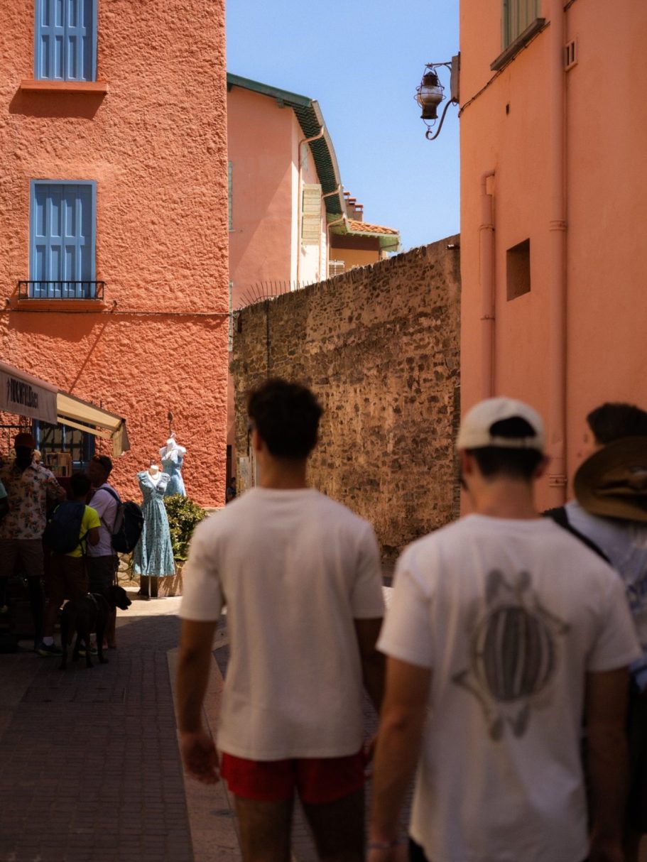 Deux personnes de dos marchent dans une ruelle étroite bordée de maisons colorées.