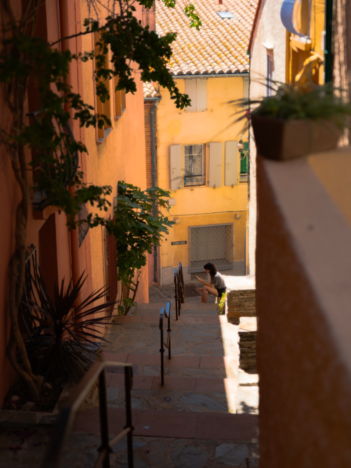 Une ruelle étroite avec des murs colorés et une personne en bas.