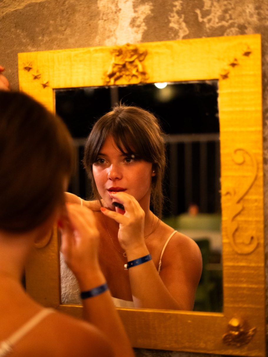 Femme se regardant dans un miroir, se maquillant dans un cadre doré.